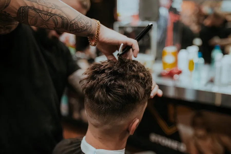 A friendly barber chatting with a customer during a haircut in a neighborhood shop.